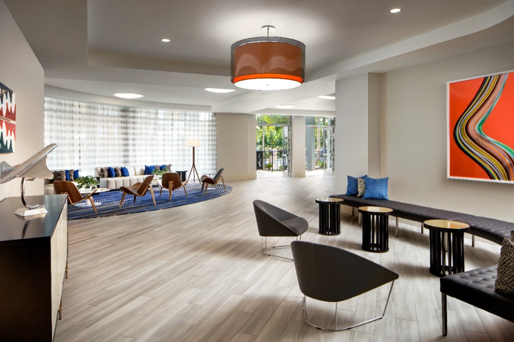 Hotel lobby lounge with sectional seating, large abstract artwork, and patio views